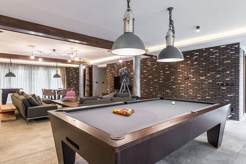 Recreational room with table for pool dark stone cladding pendant lights
